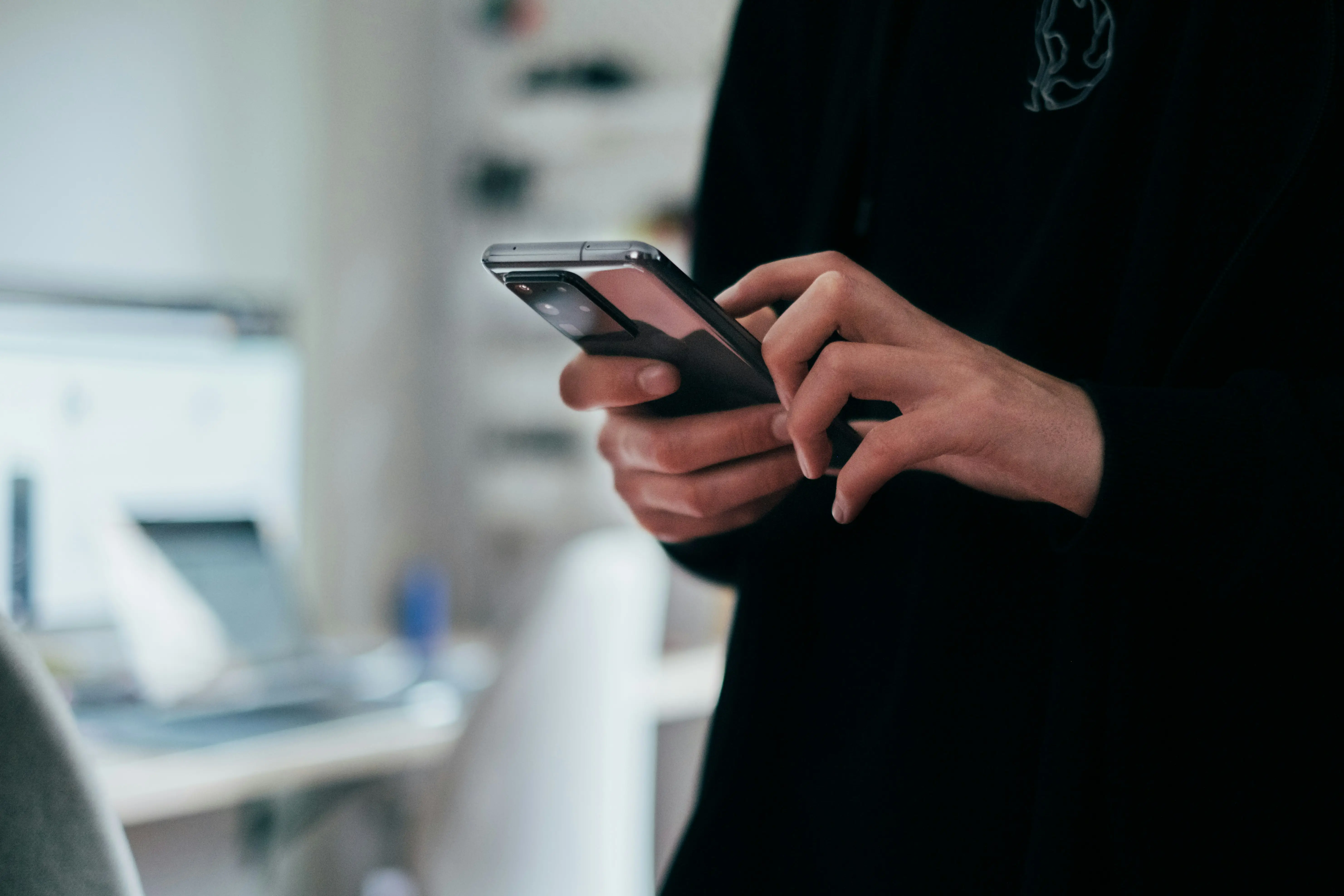 Nahaufnahme auf die Hände einer Frau, die ein Smartphone in der Hand hat und darauf tippt